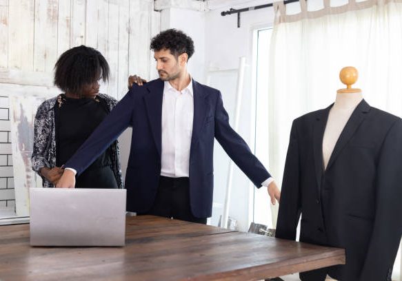 Black female tailor fitting businessman for suit in tailor shop