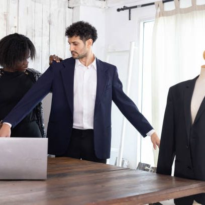 Black female tailor fitting businessman for suit in tailor shop